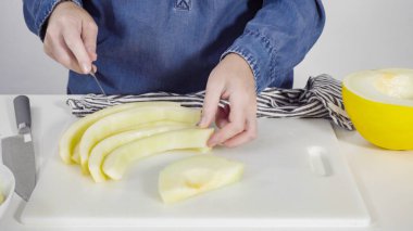 Adım adım. Beyaz kesme tahtasında kaygan altın çiğ taneli kavun.