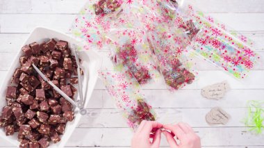 Düz yatıyordu. Adım adım. Ev yapımı macadamia şekerlemesi küçük hediye paketlerine konuyor..