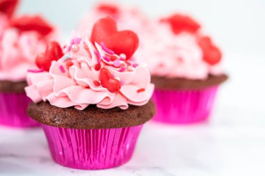 Pembe İtalyan kremalı kırmızı kadife kekler ve kalp ve öpücük şeklinde kırmızı çikolatalarla süslemeler..