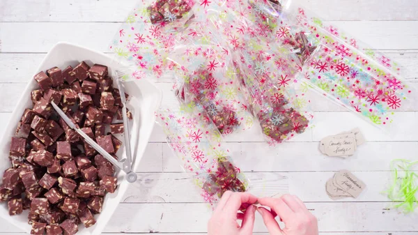 Düz yatıyordu. Adım adım. Ev yapımı macadamia şekerlemesi küçük hediye paketlerine konuyor..