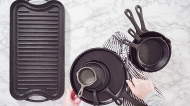 Düz yatıyordu. Mermer tezgahtaki dökme demir mutfak malzemelerinin çeşitliliği.