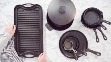 Düz yatıyordu. Mermer tezgahtaki dökme demir mutfak malzemelerinin çeşitliliği.