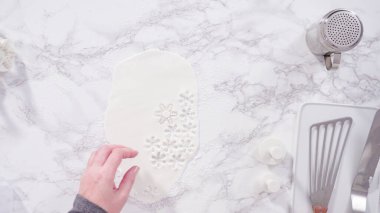 Düz yatıyordu. Adım adım. Mermer tezgahın üzerindeki beyaz fondanla kar tanelerini keserek..