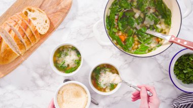 Beyaz kaselerde vejetaryen beyaz fasulye çorbası servis ediyorlar..