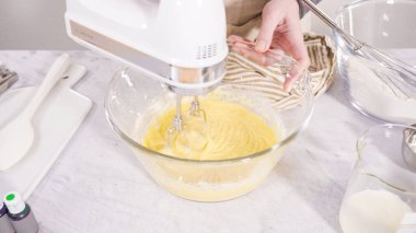 Adım adım. Vanilyalı Mardi Gras kekleri pişirmek için karışımı elektrikli mikserle karıştırıyorum..