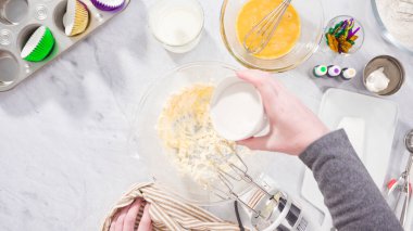 Düz yatıyordu. Adım adım. Vanilyalı Mardi Gras kekleri pişirmek için karışımı elektrikli mikserle karıştırıyorum..