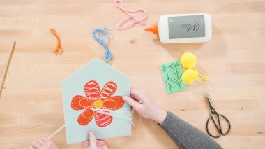 Anne çocuklara el sanatları masasında dikiş setiyle dikiş dikmeyi öğretiyor..