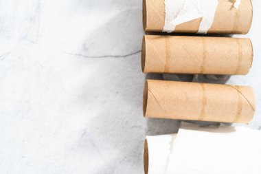 Gri arkaplanda boş tuvalet kağıdı ruloları kullanılıyor.