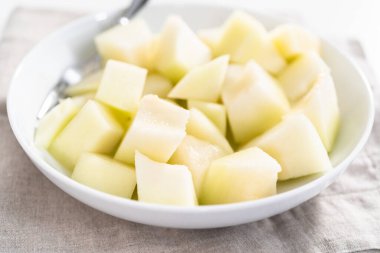 Beyaz bir kasede dilimlenmiş altın çiğ taneli kavun..