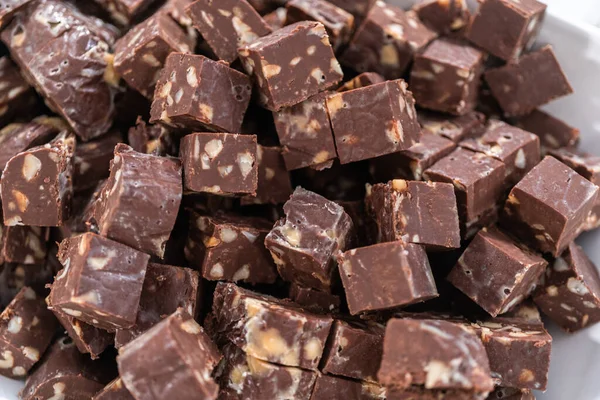 Cutting macadamia nut fudge into small cubes.