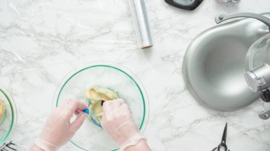 Adım adım. Düz yatıyordu. Kırmızı, beyaz ve mavi fırıldak şekerli kurabiyeler pişirmek için kurabiye hamuruna gıda boyası karıştırıyorum..