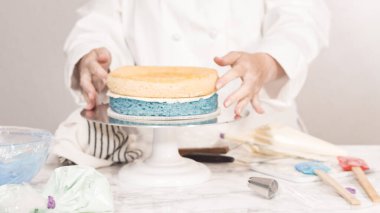 Yuvarlak üç katlı vanilyalı pasta yapmak için pasta katmanları yığılıyor.