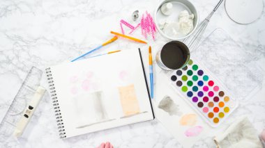 Düz yatıyordu. Baker suluboyalı bir doğum günü pastası çiziyor..