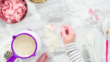Düz yatıyordu. Adım adım. Erimiş çikolatayı kar taneleri şeklinde plastik bir çikolata kalıbına döküyorum..