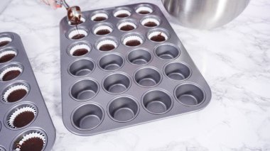 Adım adım. Mini çikolatalı kekler pişirmek için kek hamurunu mini kek kuyruklarına karıştırmak..