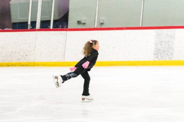 Küçük kız buz pistinde artistik patinaj yapıyor..