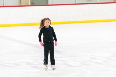 Küçük kız buz pistinde artistik patinaj yapıyor..