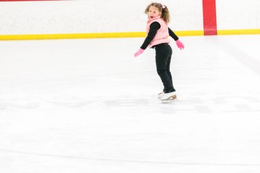 Küçük kız buz pistinde artistik patinaj yapıyor..