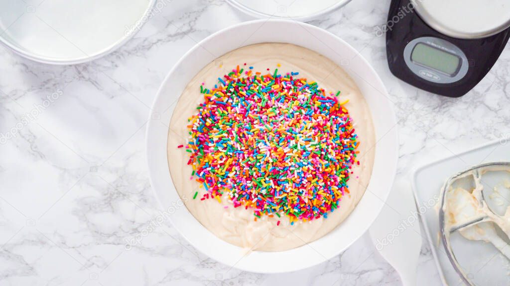 Flat lay. Step by step. Mixing in colorful sprinkles into the cake batter to make funfetti cake.