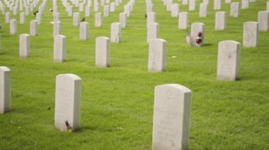 Denver, Colorado, ABD-26 Mayıs 2019 - Anma Günü 'nde Fort Logan Ulusal Mezarlığı' nda beyaz mermer mezar taşlarının yanında küçük Amerikan Bayrakları.
