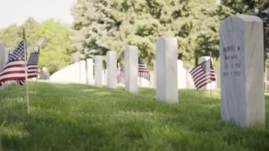 Denver, Colorado, ABD-26 Mayıs 2019 - Anma Günü 'nde Fort Logan Ulusal Mezarlığı' nda beyaz mermer mezar taşlarının yanında küçük Amerikan Bayrakları.