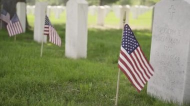 Denver, Colorado, ABD-26 Mayıs 2019 - Anma Günü 'nde Fort Logan Ulusal Mezarlığı' nda beyaz mermer mezar taşlarının yanında küçük Amerikan Bayrakları.