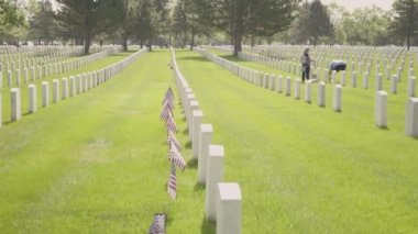 Denver, Colorado, ABD-26 Mayıs 2019 - Anma Günü 'nde Fort Logan Ulusal Mezarlığı' nda beyaz mermer mezar taşlarının yanında küçük Amerikan Bayrakları.