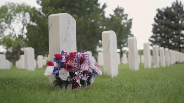 コロラド州デンバー2019年5月26日 記念の日にフォートローガン国立墓地の白い大理石の墓石の横にある小さなアメリカ国旗 — ストック動画