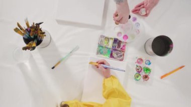 Düz yatıyordu. Uzak bir sanat projesi için annesiyle tuvale akrilik boyayla resim yapan küçük bir kız..