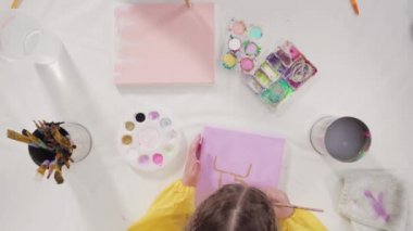 Düz yatıyordu. Uzak bir sanat projesi için annesiyle tuvale akrilik boyayla resim yapan küçük bir kız..