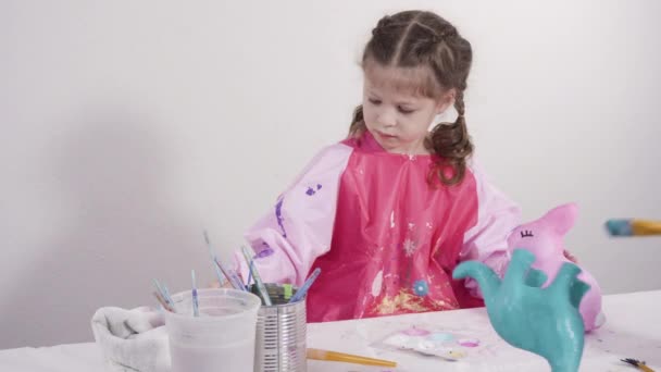 小女孩为她的家庭教育艺术项目用丙烯酸涂料画纸巾和雕像 — 图库视频影像