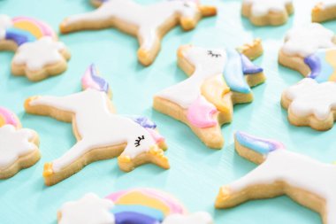 Tek boynuzlu at şeker çerezleri mavi bir arka plan üzerinde kraliyet krema ve gıda glitter ile dekore.