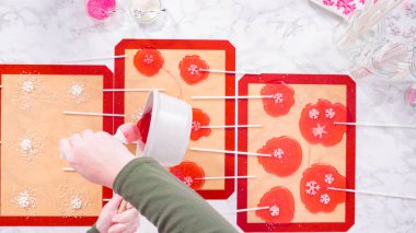 Düz yatıyordu. Ev yapımı lolipoplar yapmak için silikon paspaslara karamelize şeker dökmek..