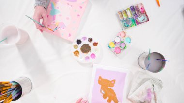 Düz yatıyordu. Uzak bir sanat projesi için annesiyle tuvale akrilik boyayla resim yapan küçük bir kız..