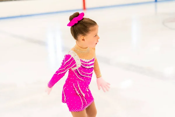 小さなフィギュアスケートでピンクのドレス練習でザ室内アイスリンク — ストック写真