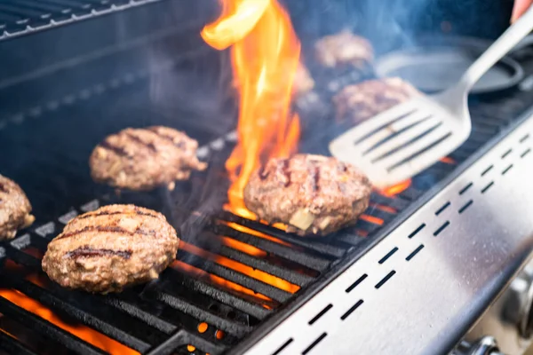Gaz ızgarasında hamburger köftesi pişirmek..