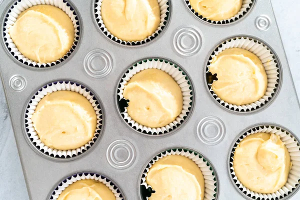 Vanilla cupcake batter in foil cupcake liners to bake Mardi Gras vanilla cupcakes.