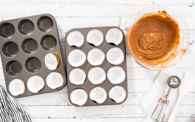 Düz yatıyordu. Çikolatalı ahududu kekleri pişirmek için folyolu kek bardaklarıyla kaplı kek tepsisi..