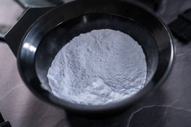 Siyah arka planda siyah plastik bir kasede saç boyası tozu..