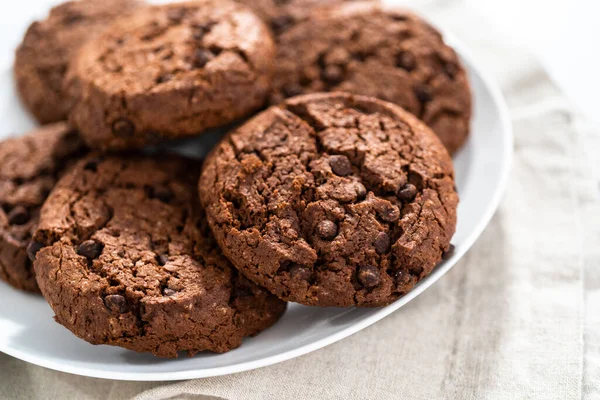 Freshly baked double chocolate chip cookies on a white plate.