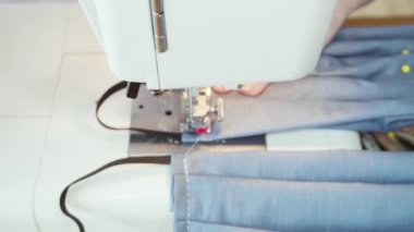 Koronavirüs salgını için dikiş makinesiyle pamuk yüz maskesi dikiyorum..