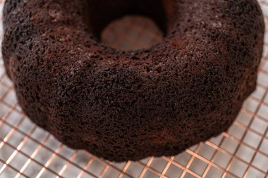 Chocolate Bundt Pastası dikkatlice tavadan çıkartılır. Yuvarlak soğutma rafına yerleştirilir. Kusursuz bir sunum ve hoş bir hoşgörü için hazırlanır..