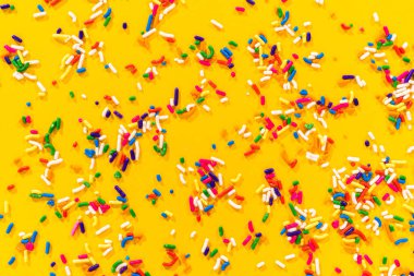 Parlak sarı bir yüzeye yayılmış renkli gökkuşağı parçacıkları. Pişirme temalı tasarımlarda, tatlı geçmişlerinde ya da parti davetiyelerinde kullanmak için mükemmel..