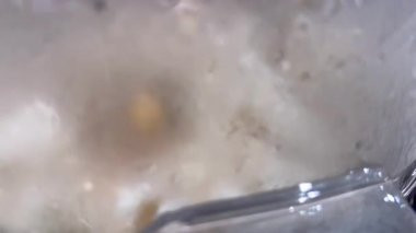 Puslu bir plastik kaplama, patlamış mısırı makinenin içinde patlamaya devam ederken kısmen gizliyor. Sıcak buhar görüntüyü bulanıklaştırıyor ve yemek pişirmenin gerçekçiliğini artırıyor..