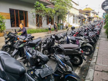 Ubud, Endonezya - Aralık 2018: Bali Ubud şehir satırında birçok motosiklet ve scooter Park. Motosiklet kask olmadan arka planda sürüş adam.