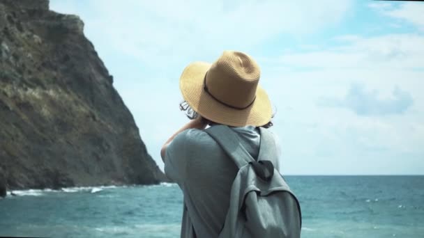 Молодая туристка в шляпе, любующаяся прекрасным видом на море — стоковое видео