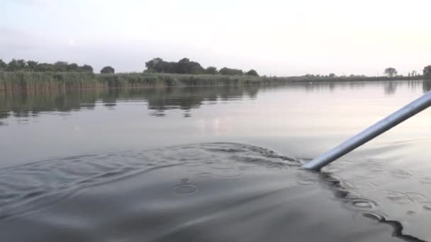 Чоловік контролює човен за допомогою весла. Крупним планом водяний спрей . — стокове відео