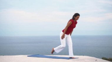 Genç kadın yoga savaşçı poz deniz kenarında yapıyor ince