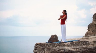 Ayakta ve bir uçurumun üzerinde meditasyon okyanus üzerinde bir kadın. Uçurumdaki Yoga.