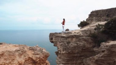 Ayakta ve bir uçurumun üzerinde meditasyon okyanus üzerinde bir kadın. Uçurumdaki Yoga.